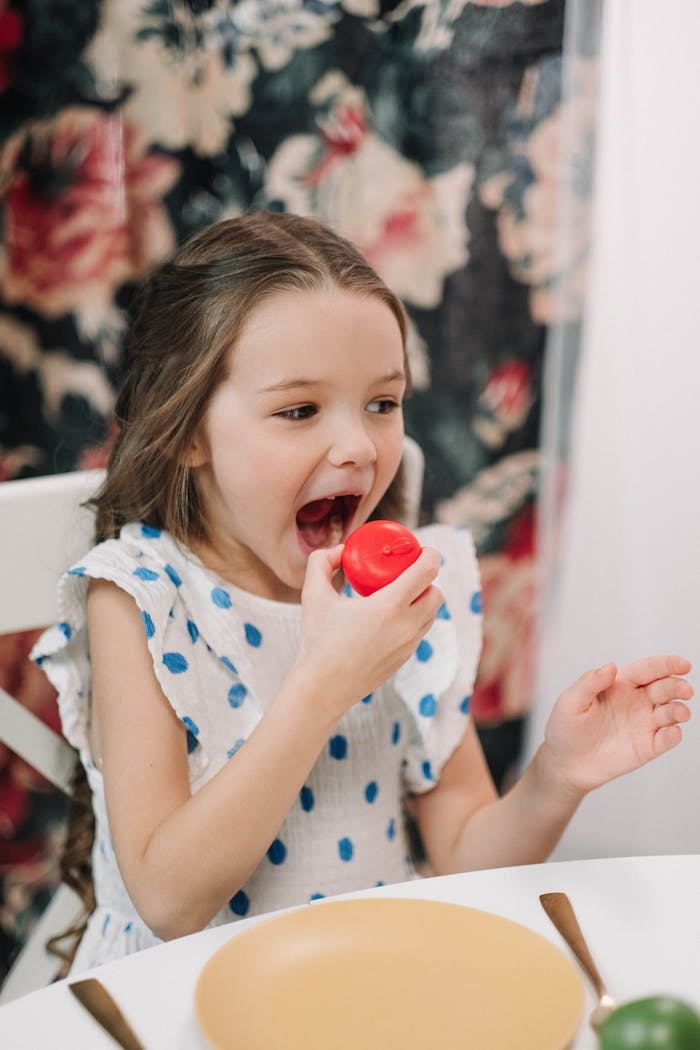 A young girl joyfully plays with a toy vegetable at a table, showcasing childhood fun.